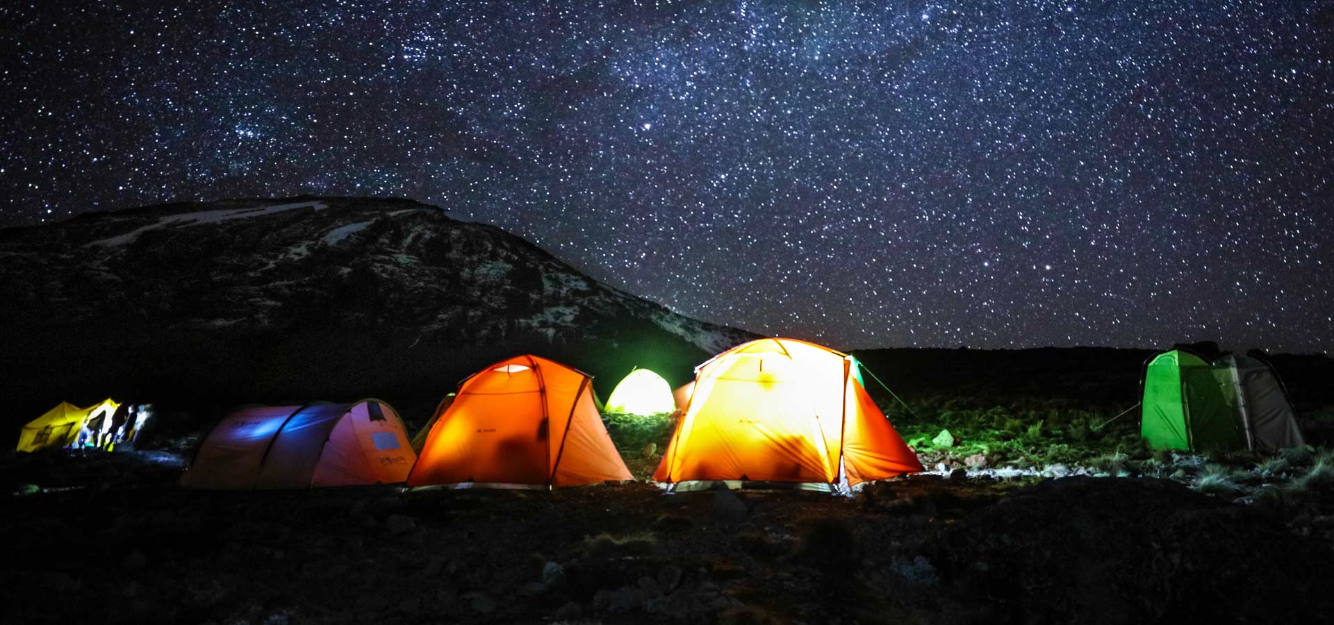Illuminated climbing tents beneath a starry sky